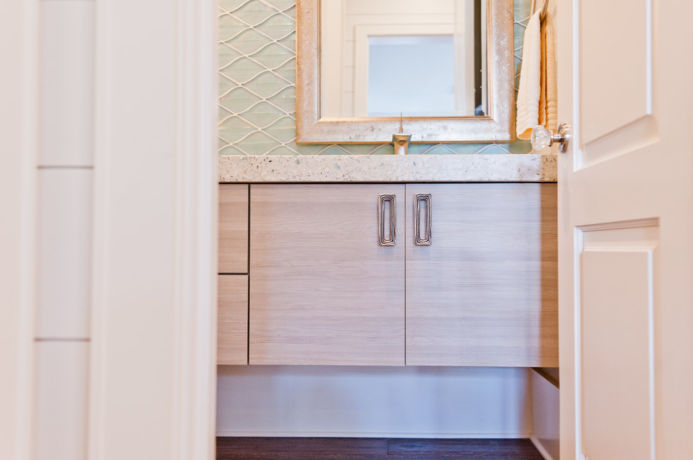 Cette image montre un WC et toilettes marin en bois clair de taille moyenne avec un placard à porte plane, un carrelage bleu, un carrelage en pâte de verre, un lavabo intégré et un plan de toilette en terrazzo.