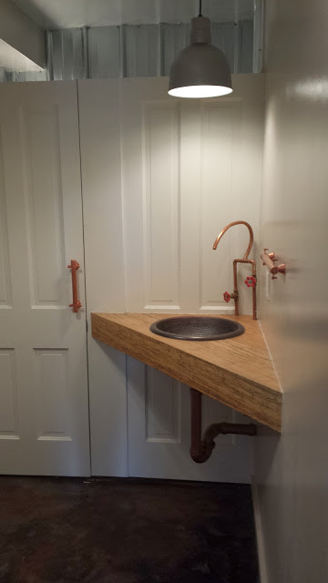 На фото: туалет среднего размера в стиле лофт с светлыми деревянными фасадами, серыми стенами, бетонным полом, накладной раковиной, столешницей из дерева и коричневым полом
