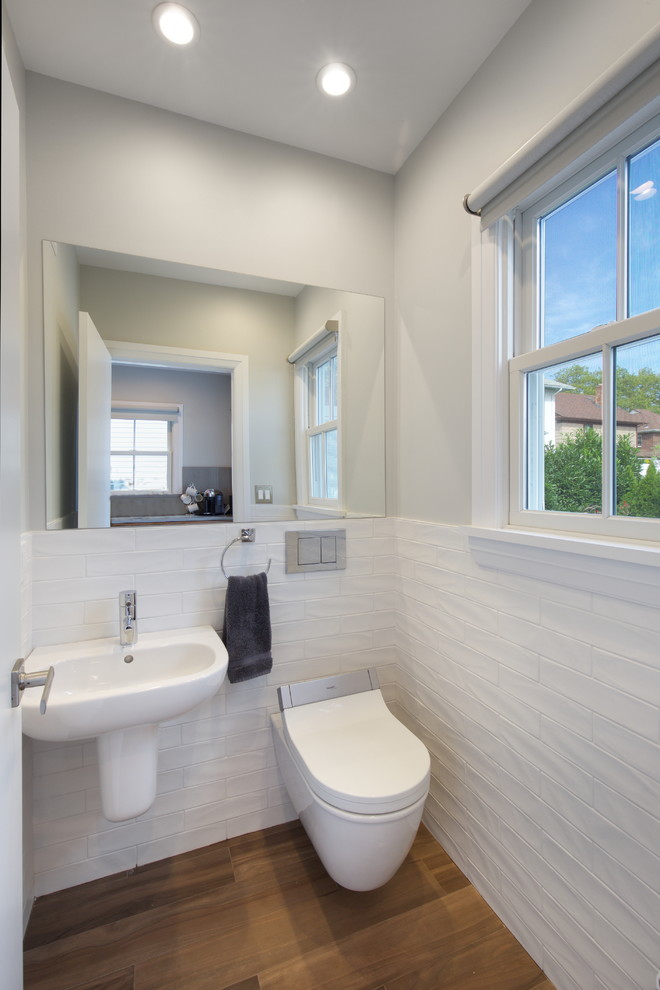 Foto di un bagno di servizio contemporaneo di medie dimensioni con WC sospeso, piastrelle bianche, piastrelle diamantate, pareti grigie, pavimento in legno massello medio, lavabo sospeso e pavimento marrone