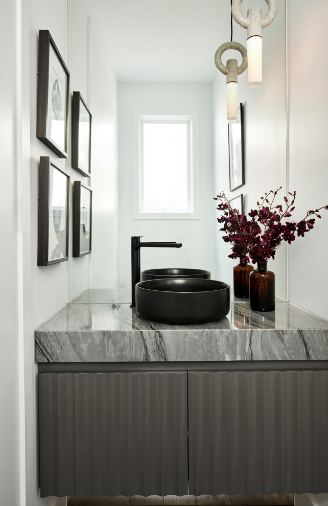 Bild på ett litet funkis grå grått toalett, med bruna skåp, ett fristående handfat och marmorbänkskiva