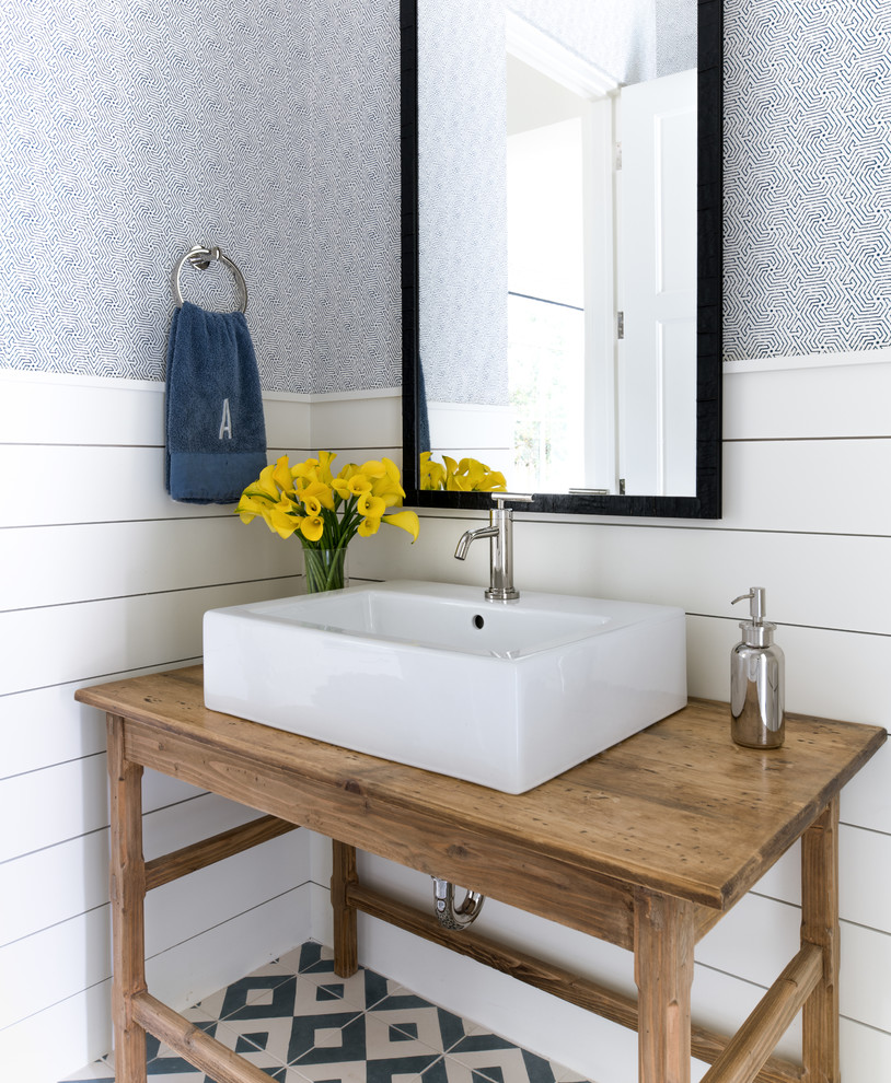 Immagine di un bagno di servizio tradizionale con consolle stile comò, ante in legno scuro, pareti blu, lavabo a bacinella, top in legno, pavimento multicolore e top marrone