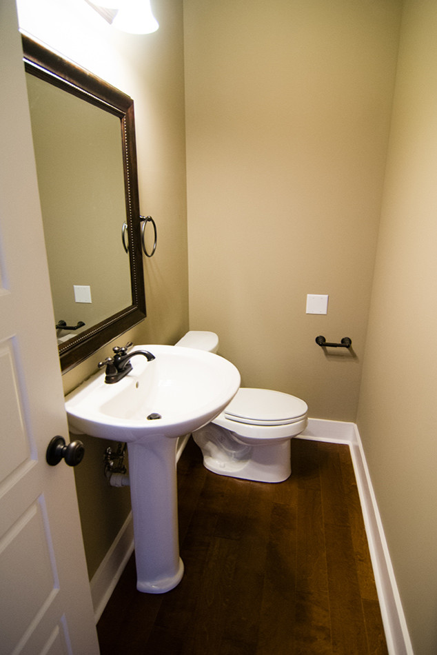Ispirazione per un piccolo bagno di servizio chic con WC a due pezzi, pareti beige, parquet scuro e lavabo a colonna