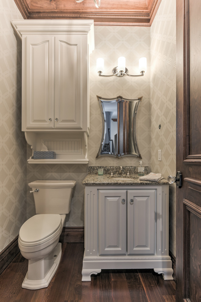 Immagine di un bagno di servizio american style di medie dimensioni con ante con riquadro incassato, ante bianche, WC a due pezzi, pareti beige, parquet scuro, lavabo sottopiano, top in granito e pavimento marrone