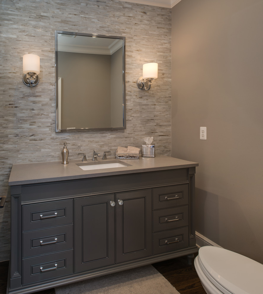 Powder room - mid-sized transitional gray tile and matchstick tile dark wood floor powder room idea in Detroit with gray cabinets, a one-piece toilet, gray walls, an undermount sink, solid surface countertops and recessed-panel cabinets