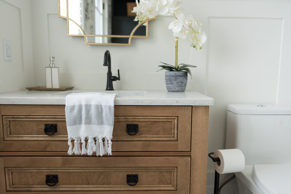 Inredning av ett amerikanskt mellanstort vit vitt toalett, med möbel-liknande, skåp i mellenmörkt trä, klinkergolv i porslin, ett undermonterad handfat, bänkskiva i kvarts och grått golv