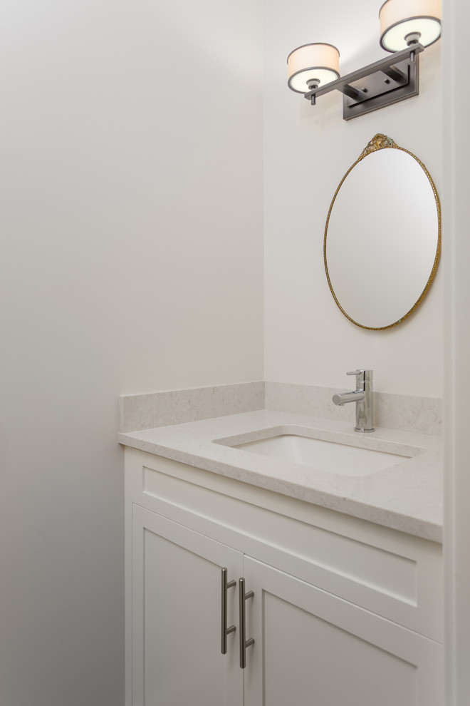 Cette image montre un petit WC et toilettes traditionnel avec un placard à porte shaker, des portes de placard blanches, WC à poser, un mur gris, un sol en bois brun, un lavabo encastré, un plan de toilette en quartz modifié, un sol marron et un plan de toilette blanc.