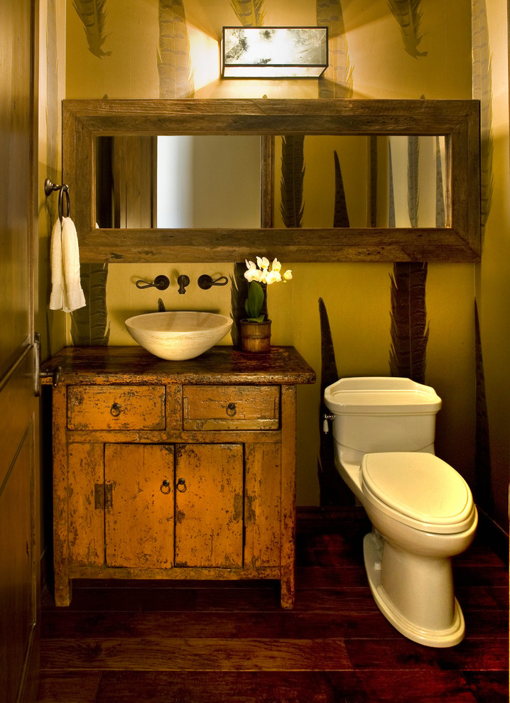 Mittelgroße Rustikale Gästetoilette mit Aufsatzwaschbecken, verzierten Schränken, orangefarbenen Schränken, Waschtisch aus Holz, Wandtoilette mit Spülkasten, dunklem Holzboden und brauner Waschtischplatte in Phoenix