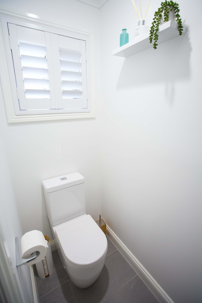 Réalisation d'un petit WC et toilettes minimaliste avec WC à poser, un mur blanc, un sol en carrelage de porcelaine et un sol gris.