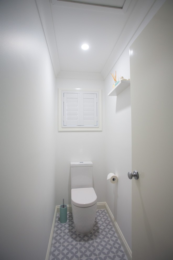 Réalisation d'un petit WC et toilettes tradition avec WC à poser, des carreaux de céramique, un mur blanc, un sol en carrelage de porcelaine, un sol bleu et un plan de toilette blanc.