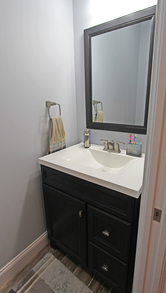 Esempio di un bagno di servizio classico di medie dimensioni con ante lisce, ante grigie, pareti grigie, pavimento in laminato e pavimento marrone