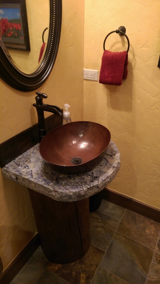 Idée de décoration pour un petit WC et toilettes chalet en bois brun avec WC à poser, un carrelage marron, des dalles de pierre, un mur jaune, un sol en carrelage de céramique, une vasque et un plan de toilette en granite.