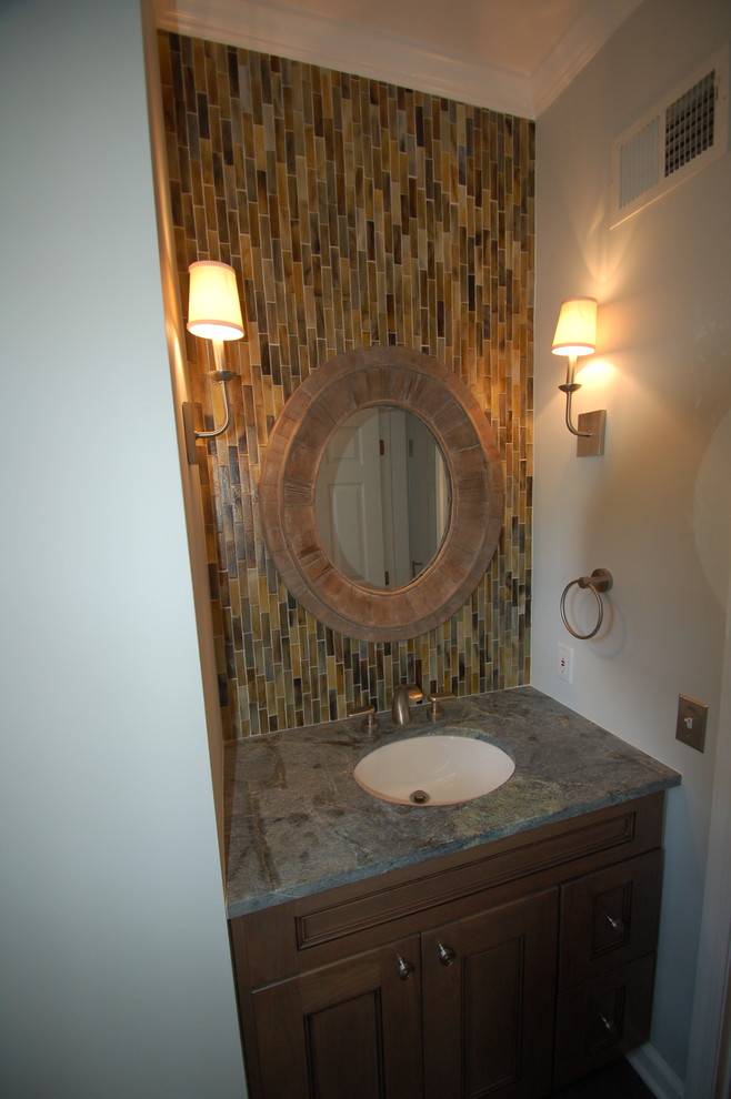 На фото: маленький туалет в классическом стиле с фасадами с выступающей филенкой, фасадами цвета дерева среднего тона, унитазом-моноблоком, разноцветной плиткой, удлиненной плиткой, серыми стенами, врезной раковиной и столешницей из гранита для на участке и в саду с