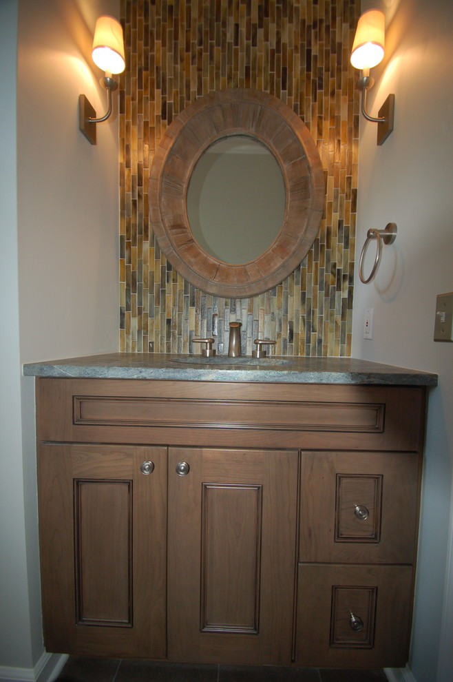 Klassisk inredning av ett litet toalett, med luckor med upphöjd panel, skåp i mellenmörkt trä, en toalettstol med hel cisternkåpa, flerfärgad kakel, stickkakel, grå väggar, ett undermonterad handfat och granitbänkskiva