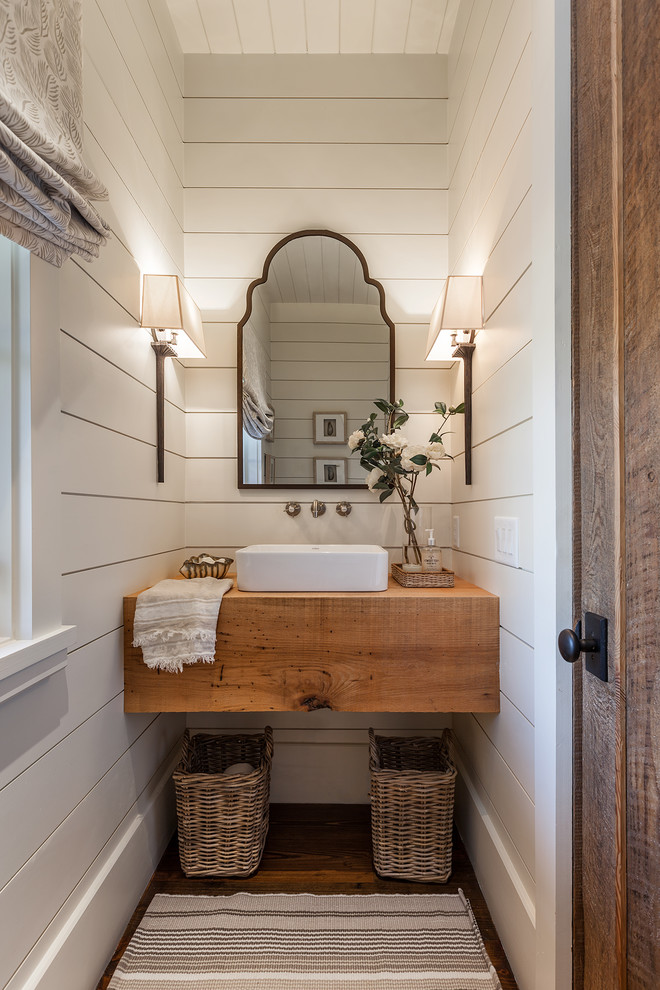 Example of a small country dark wood floor and brown floor powder room design in Other with a vessel sink, white walls, wood countertops and brown countertops