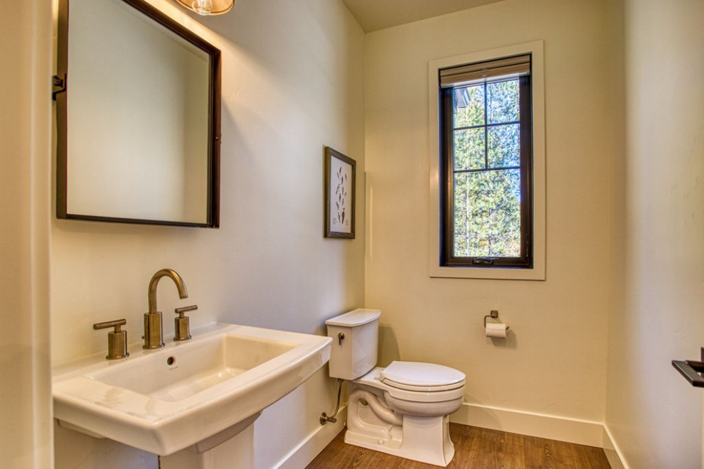Immagine di un piccolo bagno di servizio country con WC a due pezzi, pareti bianche, pavimento in legno massello medio, lavabo a colonna e pavimento marrone