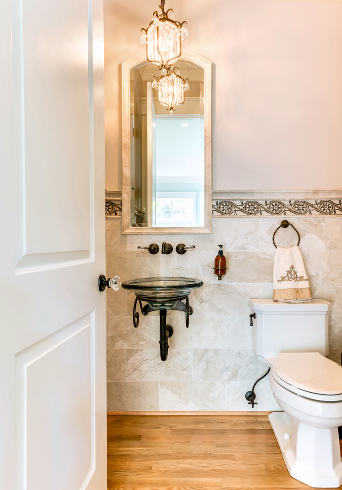 Klassisk inredning av ett mellanstort toalett, med en toalettstol med hel cisternkåpa, beige kakel, porslinskakel, rosa väggar, mellanmörkt trägolv, ett väggmonterat handfat och brunt golv