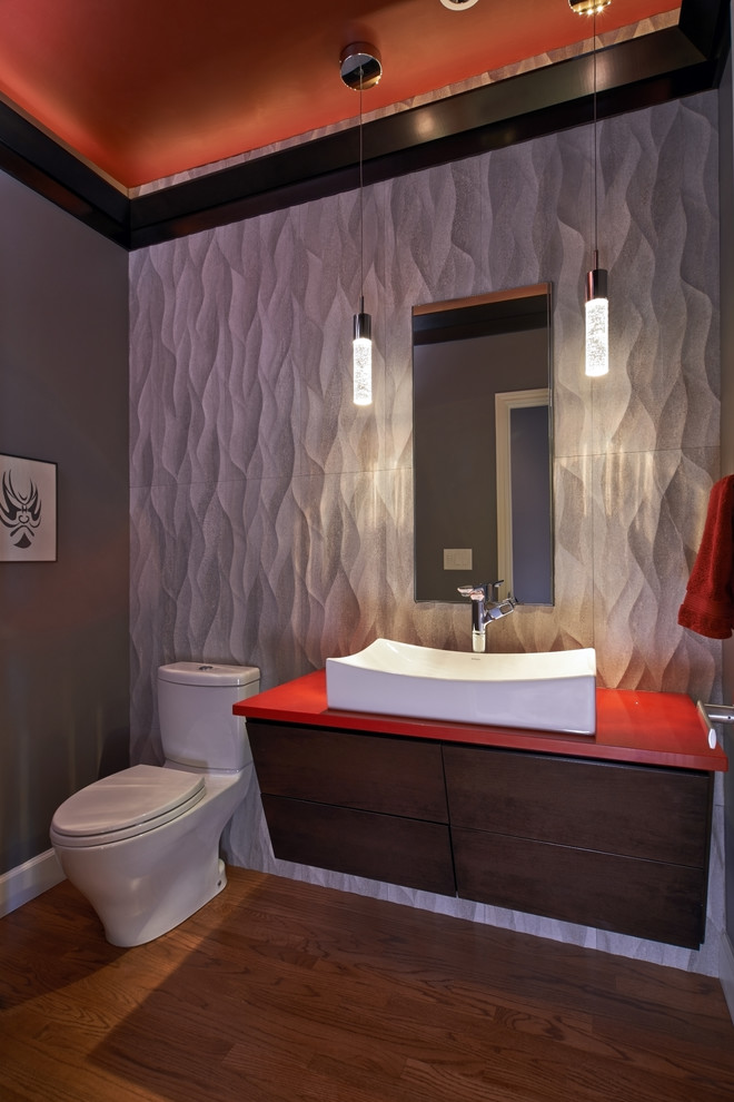 Idée de décoration pour un WC et toilettes design en bois brun avec un placard à porte plane, WC à poser, un carrelage gris, des carreaux de porcelaine, un mur gris, un sol en bois brun, un plan de toilette en quartz modifié et un plan de toilette rouge.