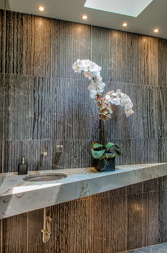 Immagine di un piccolo bagno di servizio design con WC sospeso, piastrelle grigie, piastrelle in gres porcellanato, pareti grigie, pavimento in gres porcellanato, lavabo sottopiano, top in marmo e pavimento grigio