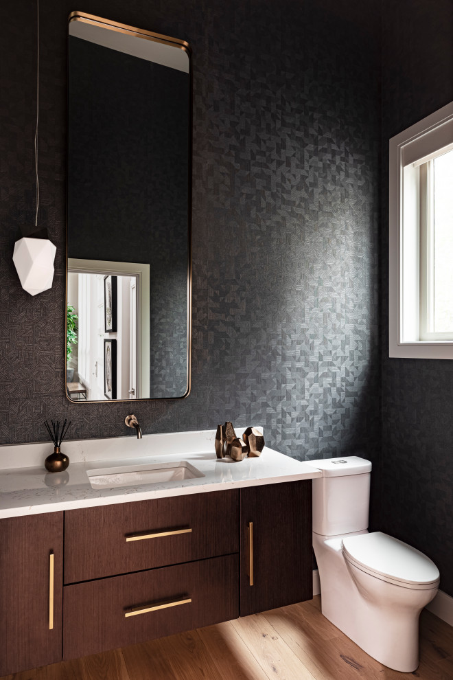 Modern inredning av ett flerfärgad flerfärgat toalett, med släta luckor, skåp i mellenmörkt trä, en toalettstol med separat cisternkåpa, grå väggar, mellanmörkt trägolv, ett undermonterad handfat, bänkskiva i kvarts och brunt golv