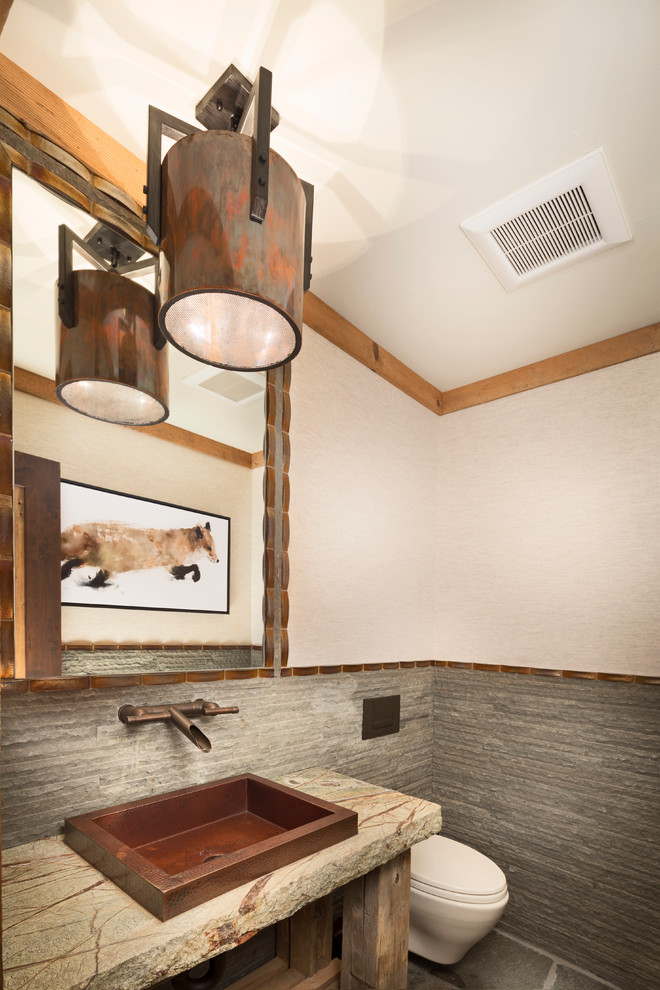 Foto på ett litet rustikt grå toalett, med öppna hyllor, en vägghängd toalettstol, grå kakel, beige väggar, ett fristående handfat, skåp i slitet trä, stenkakel, granitbänkskiva och skiffergolv
