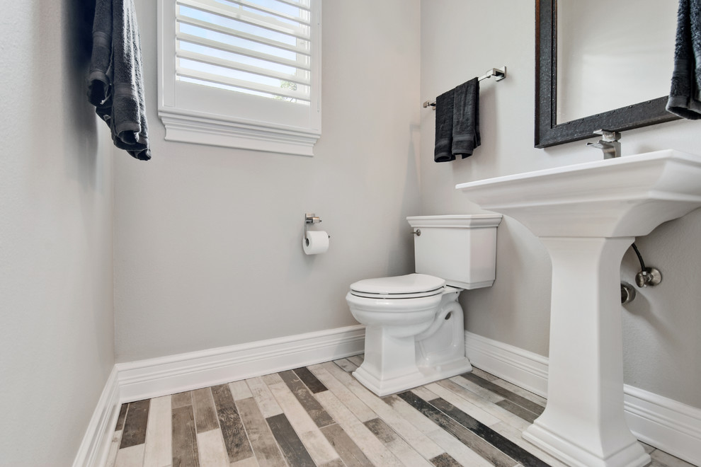 Immagine di un bagno di servizio classico di medie dimensioni con WC a due pezzi, pareti beige, pavimento in vinile, lavabo a colonna e pavimento multicolore