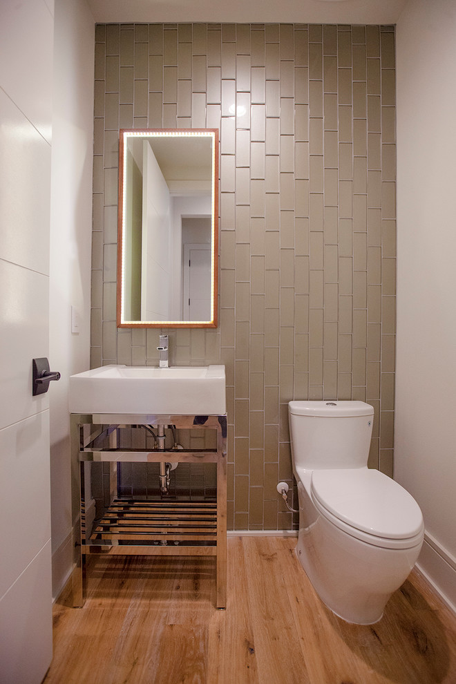 Réalisation d'un WC et toilettes design de taille moyenne avec un placard sans porte, WC à poser, un carrelage beige, un carrelage vert, un carrelage en pâte de verre, un mur gris, un sol en bois brun et un lavabo intégré.