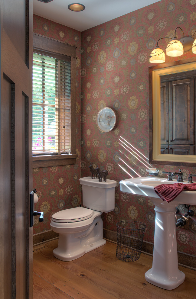 Urige Gästetoilette mit Wandtoilette mit Spülkasten, bunten Wänden, braunem Holzboden, Sockelwaschbecken und braunem Boden in Minneapolis