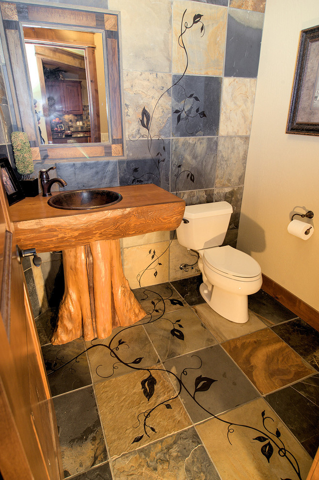 Mid-sized arts and crafts brown tile and stone tile slate floor powder room photo in Seattle with a drop-in sink, furniture-like cabinets, medium tone wood cabinets, wood countertops, a two-piece toilet and beige walls