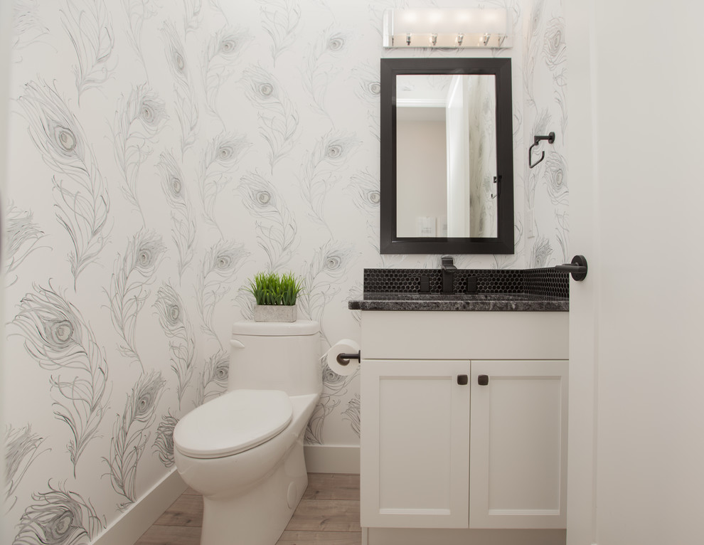 Klassische Gästetoilette mit Schrankfronten mit vertiefter Füllung, weißen Schränken, Toilette mit Aufsatzspülkasten, weißer Wandfarbe, hellem Holzboden, Unterbauwaschbecken, beigem Boden und grauer Waschtischplatte in Edmonton