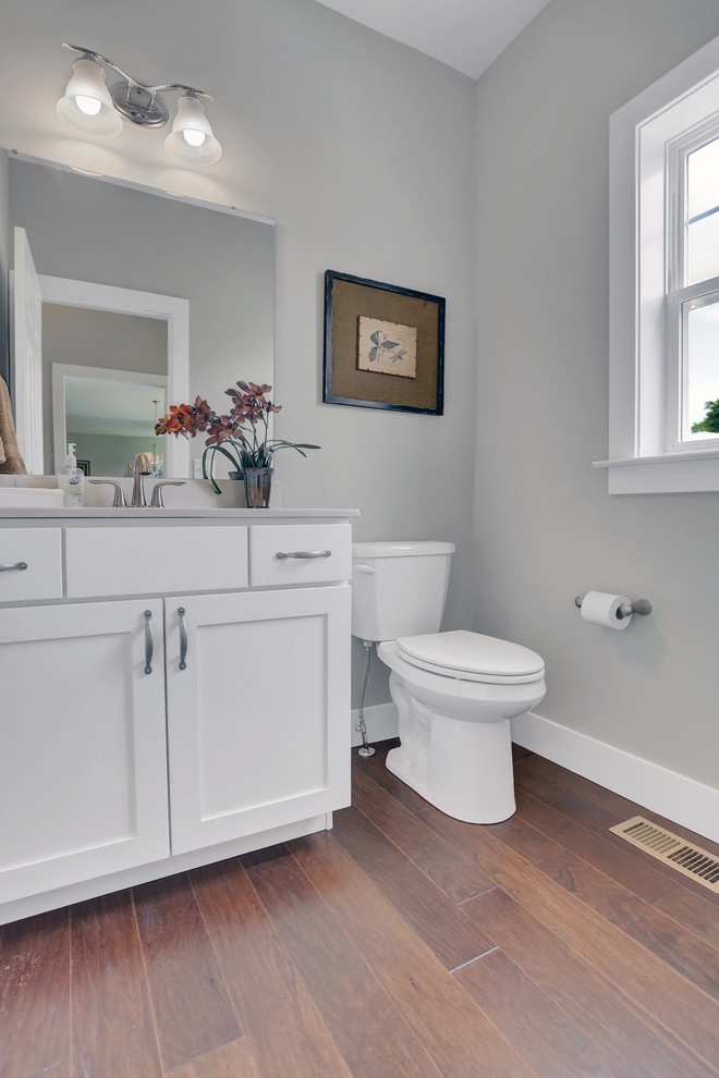 Idee per un grande bagno di servizio stile americano con ante bianche, WC a due pezzi, pareti beige, pavimento in legno massello medio, lavabo integrato e top in marmo
