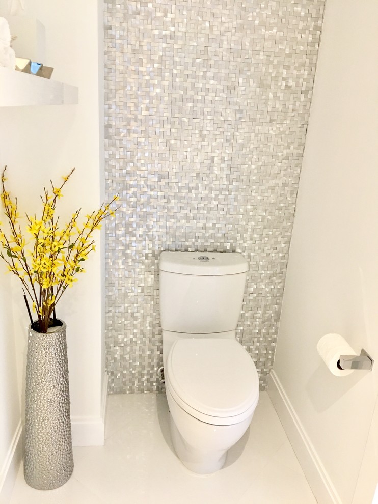 Foto på ett litet funkis toalett, med släta luckor, vita skåp, en toalettstol med separat cisternkåpa, vit kakel, kakel i metall, vita väggar, klinkergolv i porslin, ett integrerad handfat, bänkskiva i kvartsit och vitt golv