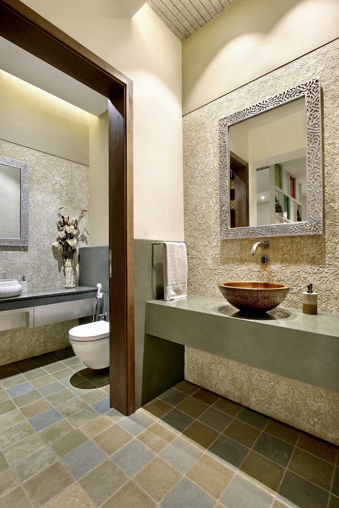 Example of a tuscan brown tile powder room design in Other with flat-panel cabinets, gray cabinets, a wall-mount toilet, beige walls and a vessel sink
