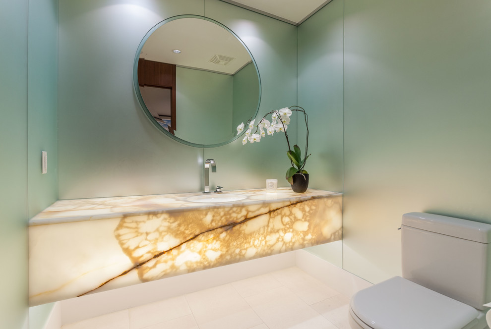 Esempio di un bagno di servizio design di medie dimensioni con ante lisce, WC monopezzo, lavabo da incasso e top in onice