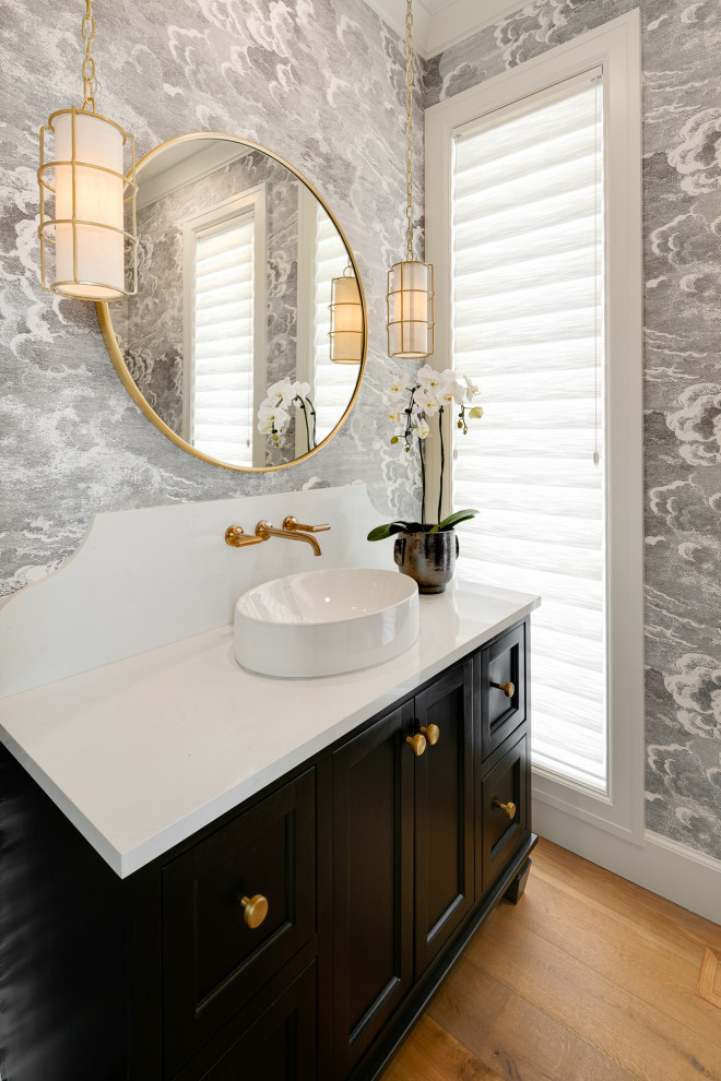 Immagine di un bagno di servizio tradizionale con ante in stile shaker, ante nere, pareti grigie, pavimento in legno massello medio, lavabo a bacinella, pavimento marrone e top bianco
