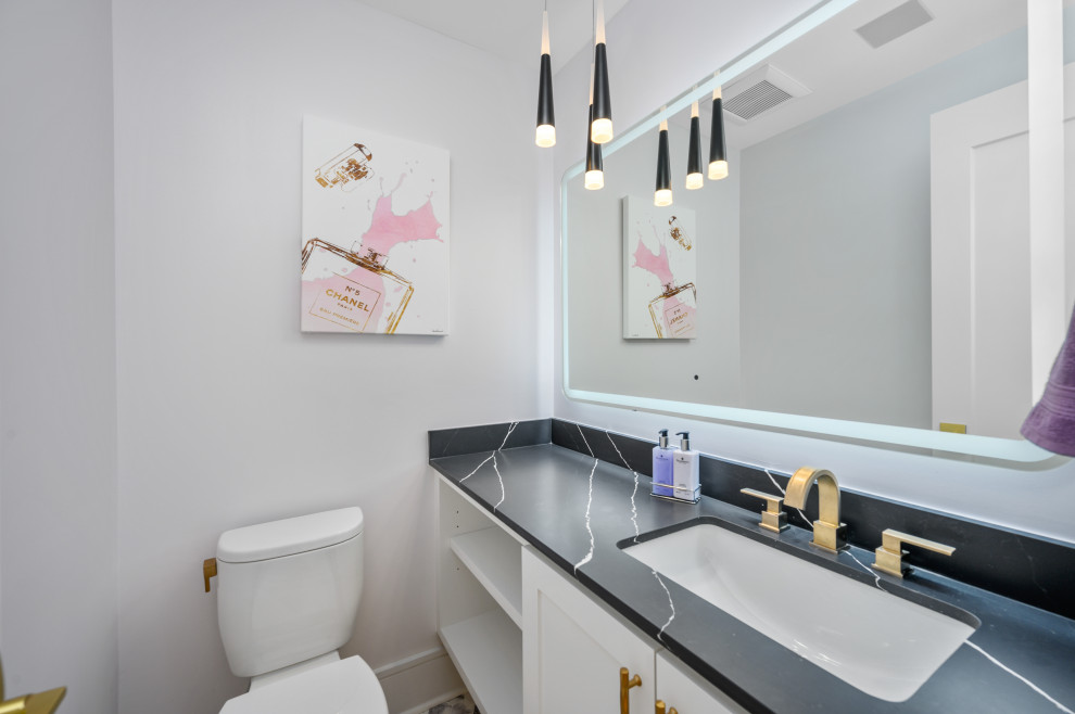 Powder room - mid-sized modern marble floor and purple floor powder room idea in Houston with raised-panel cabinets, white cabinets, a two-piece toilet, gray walls, an undermount sink, solid surface countertops and black countertops