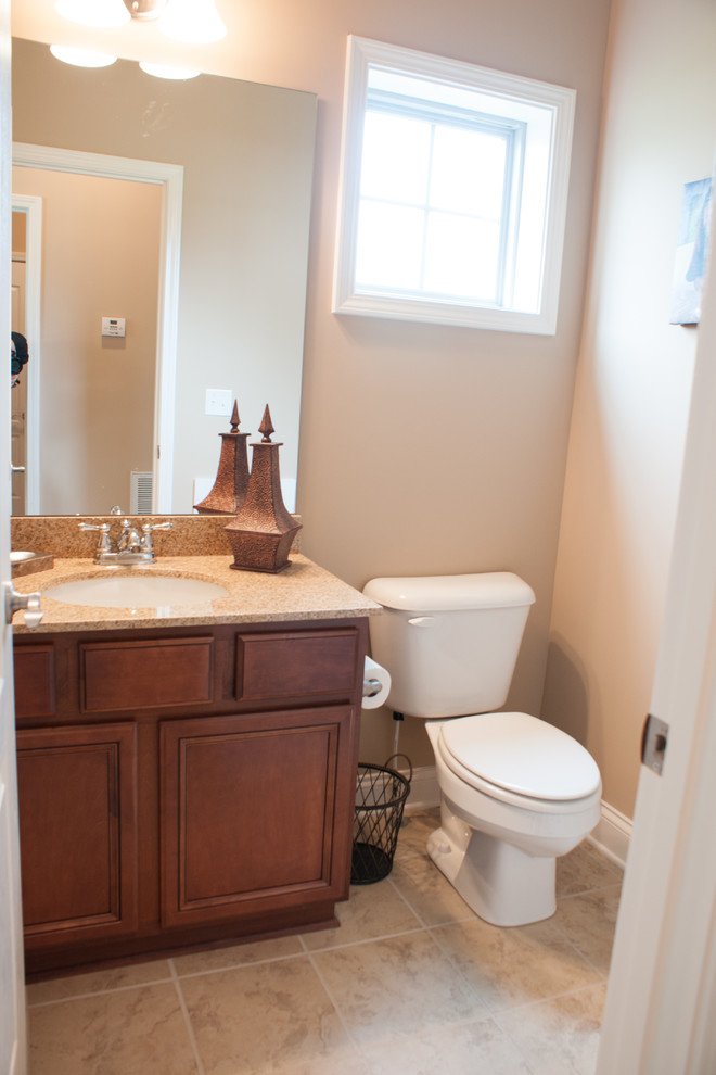 Example of a classic beige tile ceramic tile powder room design in Other with an undermount sink, medium tone wood cabinets, granite countertops, a two-piece toilet, beige walls and recessed-panel cabinets