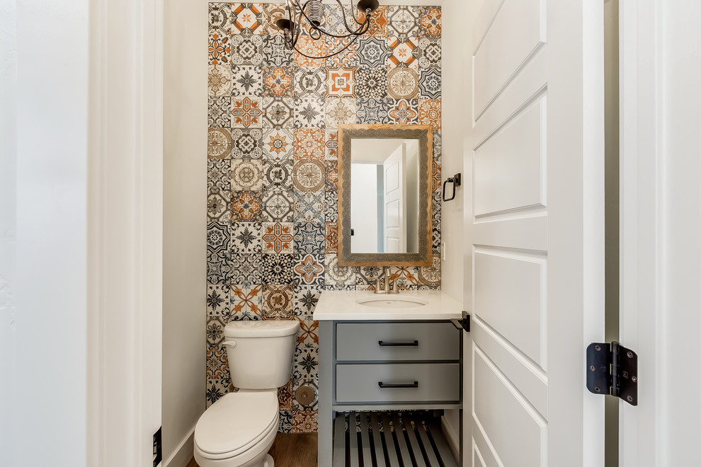 Country cloakroom in Other with flat-panel cabinets, grey cabinets, a two-piece toilet, multi-coloured tiles, white walls, medium hardwood flooring, a submerged sink, brown floors and white worktops.