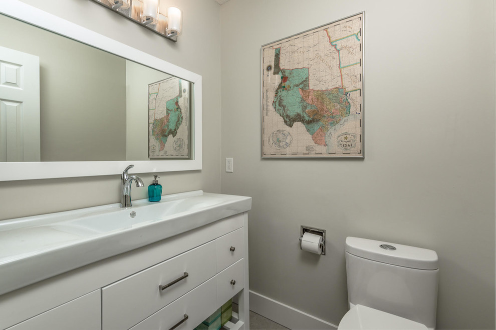 Mid-sized minimalist vinyl floor and beige floor powder room photo in Vancouver with flat-panel cabinets, white cabinets, a one-piece toilet, beige walls, an integrated sink, solid surface countertops and white countertops