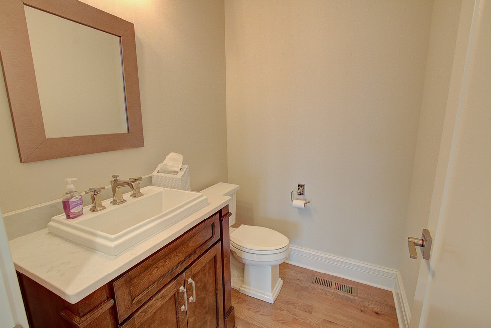 Réalisation d'un petit WC et toilettes tradition en bois foncé avec un placard avec porte à panneau encastré, un mur gris, parquet clair, une vasque, un plan de toilette en quartz modifié, un sol beige et un plan de toilette blanc.