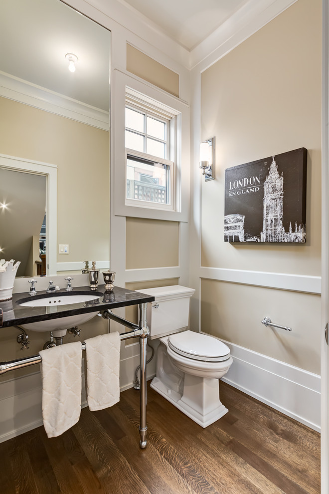 Cette image montre un WC et toilettes craftsman de taille moyenne avec un lavabo encastré, un plan de toilette en granite, WC séparés, un mur beige et un sol en bois brun.