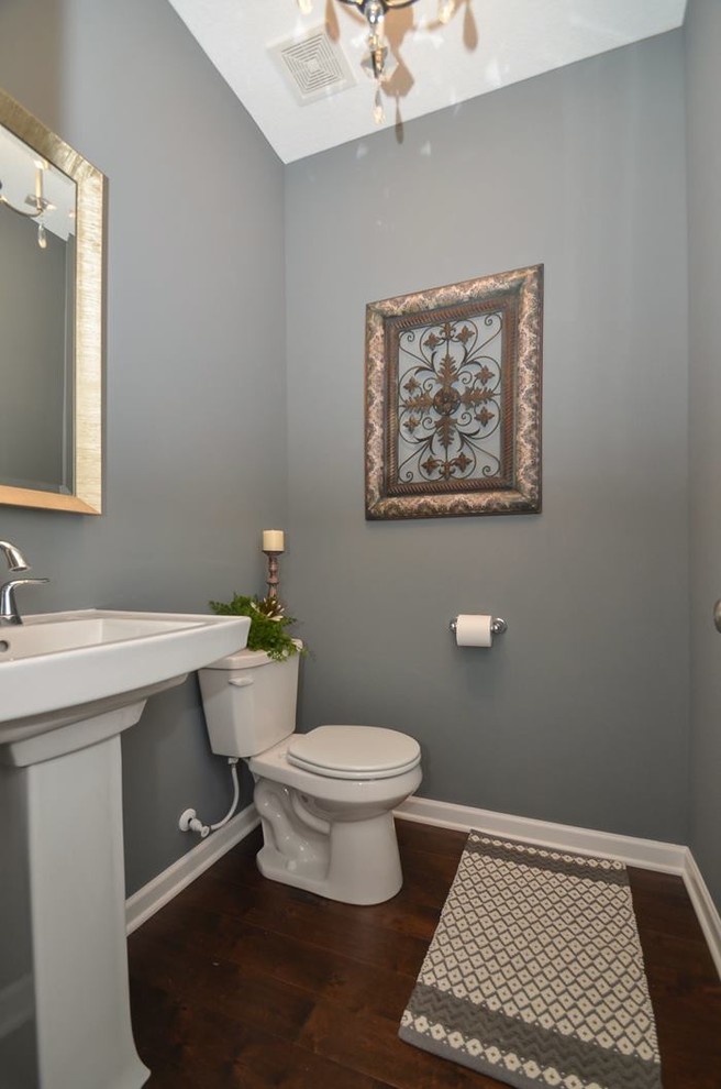 Inspiration för klassiska toaletter, med ett piedestal handfat, en toalettstol med separat cisternkåpa, blå väggar och mellanmörkt trägolv
