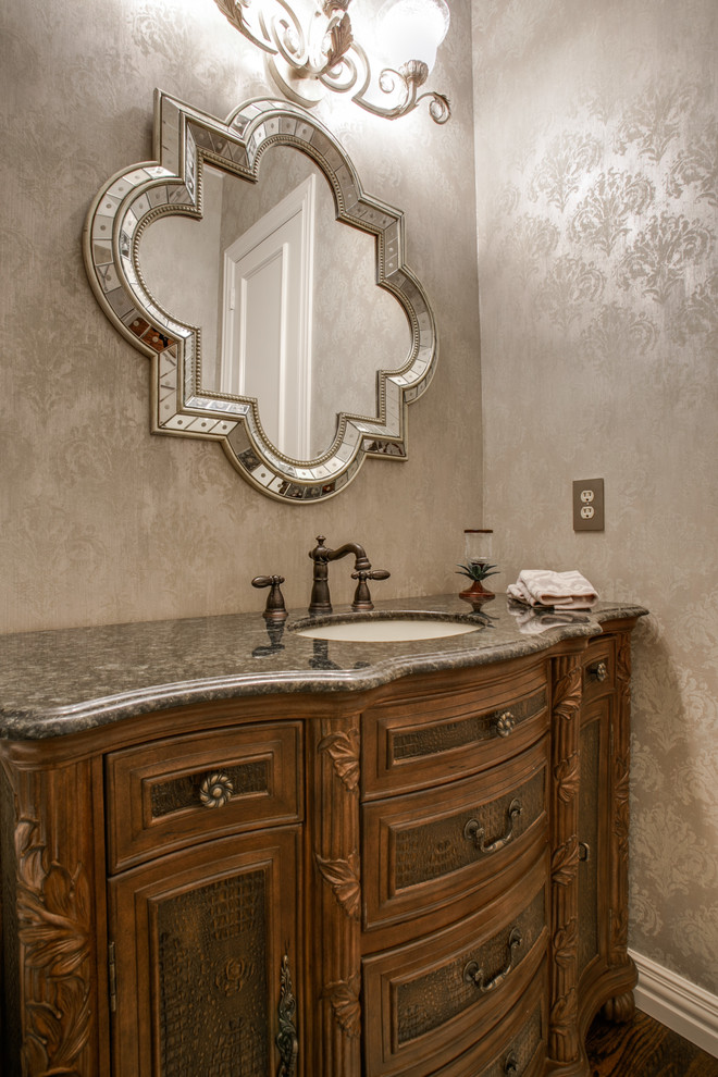 Aménagement d'un WC et toilettes classique en bois brun de taille moyenne avec un lavabo posé, un plan de toilette en granite, un mur gris, parquet foncé et un placard en trompe-l'oeil.