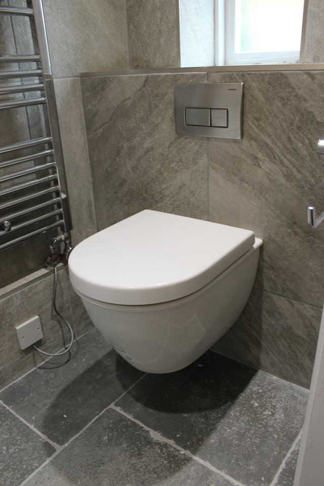 ドーセットにある小さなカントリー風のおしゃれなトイレ・洗面所 (フラットパネル扉のキャビネット、白いキャビネット、壁掛け式トイレ、ベージュのタイル、磁器タイル、ベージュの壁、オーバーカウンターシンク) の写真