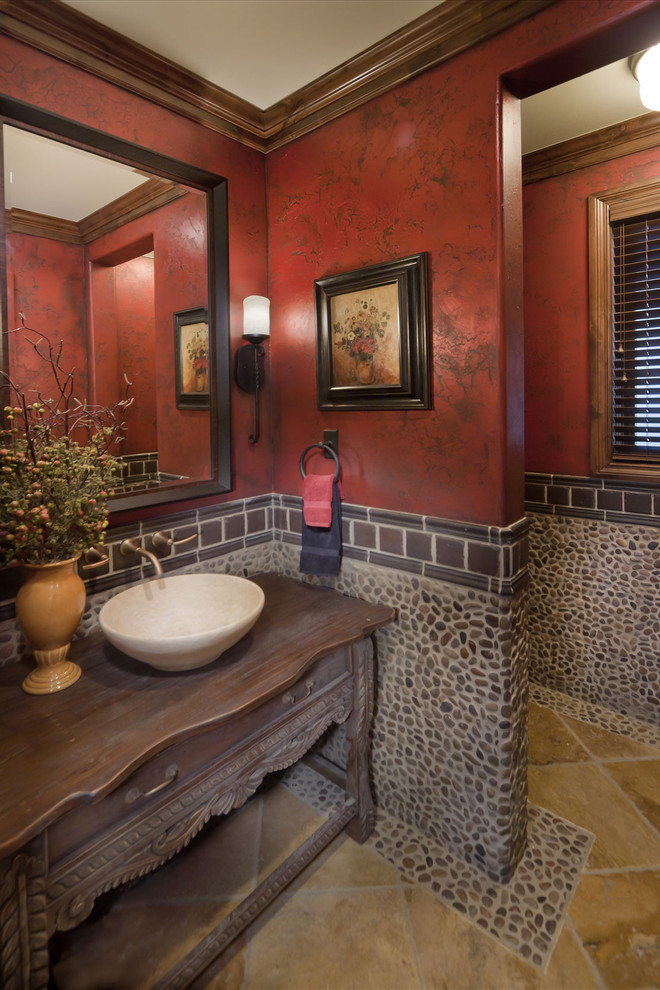 На фото: туалет в средиземноморском стиле с галечной плиткой, настольной раковиной и красными стенами с