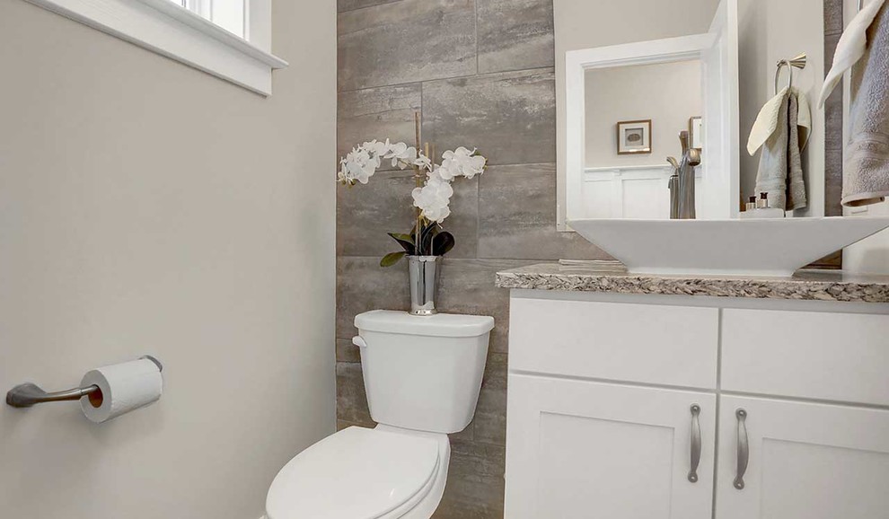 This is an example of a medium sized classic cloakroom in Other with white cabinets, a two-piece toilet, grey tiles, metro tiles, grey walls, medium hardwood flooring, a vessel sink and granite worktops.