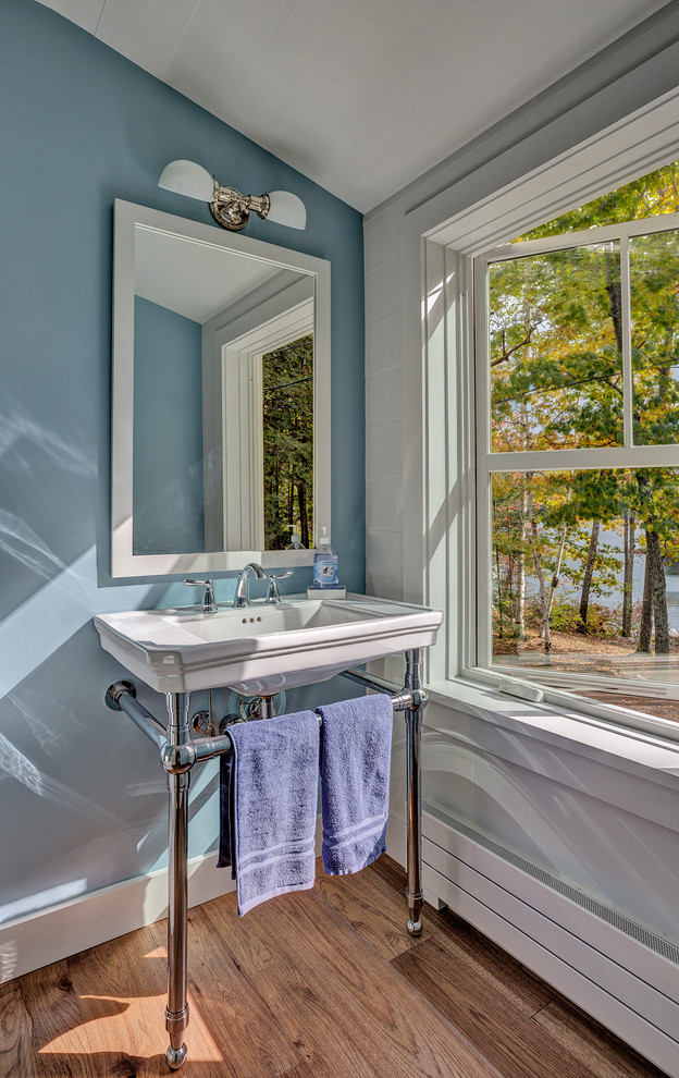 Источник вдохновения для домашнего уюта: туалет в морском стиле с унитазом-моноблоком, синими стенами, паркетным полом среднего тона, консольной раковиной и коричневым полом