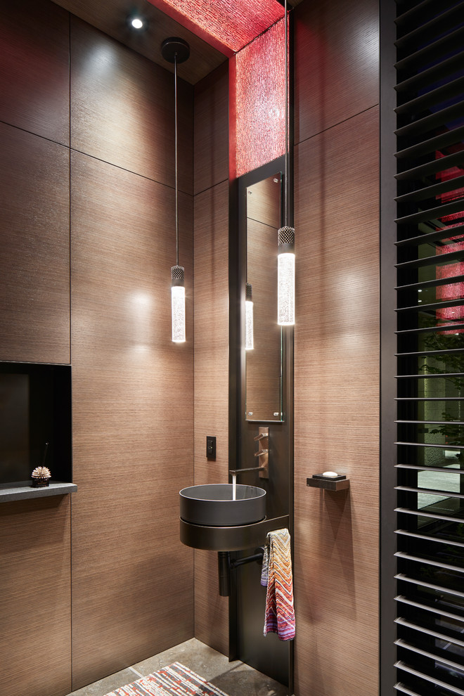 Exempel på ett modernt toalett, med bruna väggar och ett fristående handfat