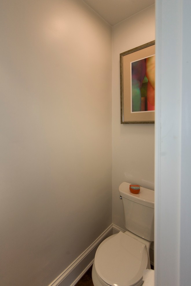 Inredning av ett modernt litet toalett, med ett piedestal handfat, skåp i mellenmörkt trä, en toalettstol med separat cisternkåpa, vita väggar och mellanmörkt trägolv