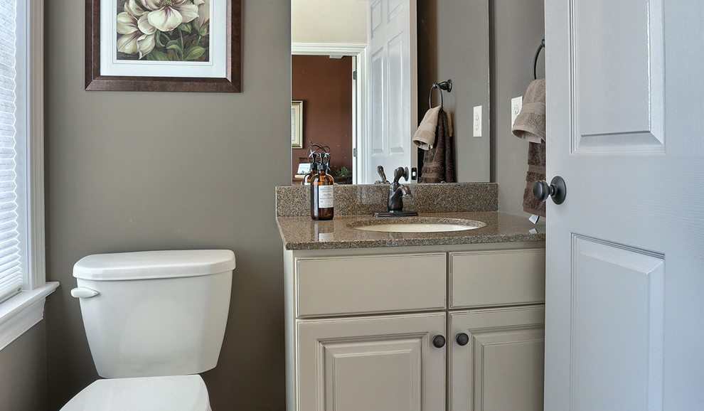 Idee per un bagno di servizio stile americano di medie dimensioni con parquet scuro, ante bianche, WC a due pezzi, lavabo integrato e top in granito