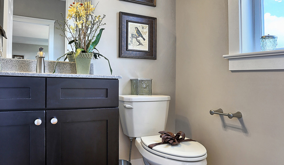 Foto di un bagno di servizio stile americano di medie dimensioni con ante lisce, ante nere, pavimento in legno massello medio, top in marmo, pareti beige e WC a due pezzi
